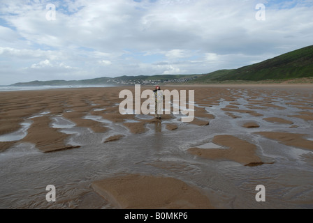 Ein Urlauber genießt einen Moment der Einsamkeit an einem einsamen Strand in der Nähe von Woolacombe North Devon England UK. Stockfoto