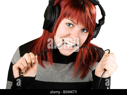 Niedliche Mädchen mit roten Haaren beißen das Kabel der Kopfhörer beim Musikhören Studioaufnahme Stockfoto
