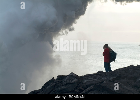 Mann fotografiert Dampf aus Lava fließt in das Meer, Hawaiʻi-Volcanoes-Nationalpark, Insel Hawaii (Big Island), Ha Stockfoto
