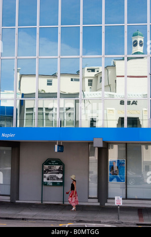 Art Deco Gebäude spiegeln sich in einem modernen Glasgebäude mit vorbeifahrenden Fußgängern in Napier, Neuseeland Stockfoto