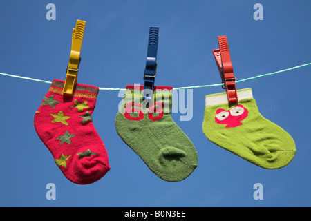 Drei verschiedene Baby-Socken auf einer Wäscheleine trocknen. Stockfoto