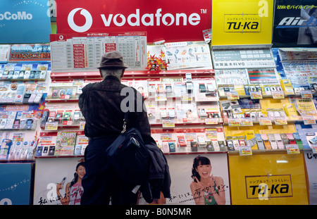 9. November 2004 - Kunden suchen auf Mobiltelefone vor einem Geschäft in Tokio Akihabara, besser bekannt als Electric Town. Stockfoto