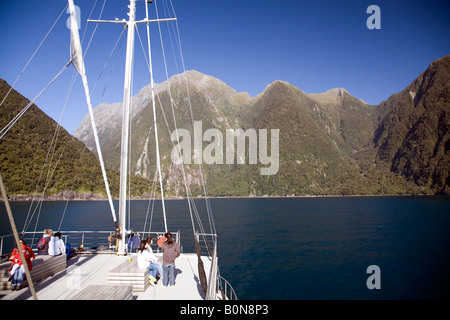 Touristen auf dem Bug eines Bootes in Milford Sound, Fiordland, Neuseeland Stockfoto