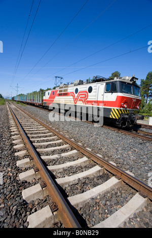 Langen Güterzug mit E-Lok und flatcars für Verkehr anmelden. Moderne Betonschwellen (TIES) auf Schienen, Finnland Stockfoto