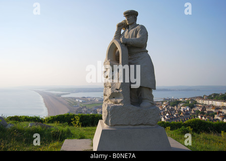 "Spirit of Portland" Statue mit Chesil Beach hinter Isle of Portland, Dorset, England, United Kingdom Stockfoto