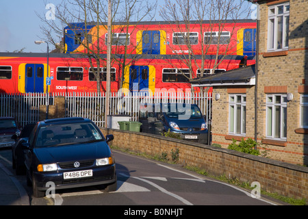 Zwei vorbeifahrende Züge fahren in einem Wohngebiet, auf verschiedenen Gleisen und in der Nähe von Parkwagen und Wohngebäuden. Twickenham, West London. UK. Stockfoto