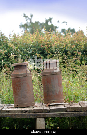 ZWEI ROSTEN MILCHKANNEN AUF EINEM FELDWEG UK Stockfoto