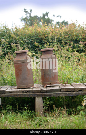 ZWEI ROSTEN MILCHKANNEN AUF EINEM FELDWEG UK Stockfoto