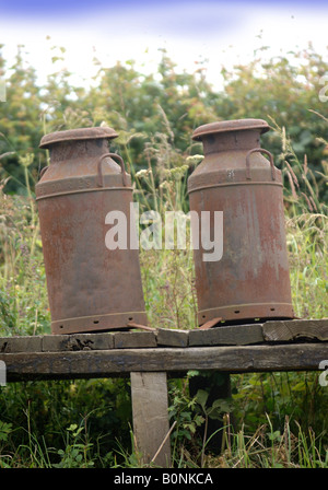 ZWEI ROSTEN MILCHKANNEN AUF EINEM FELDWEG UK Stockfoto