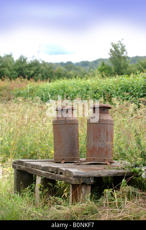 ZWEI ROSTEN MILCHKANNEN AUF EINEM FELDWEG UK Stockfoto