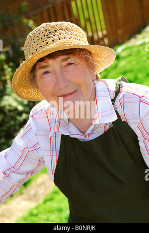 Porträt einer älteren Frau im Garten Schürze und Mütze Stockfoto