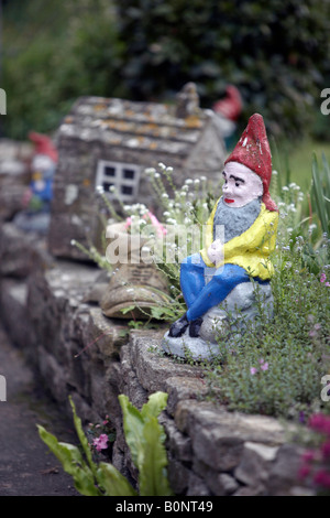 Ein Gartenzwerg, sitzend in einem herrlich gut etablierten Country-Garten. Stockfoto