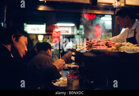Menschen Essen in einem der schummrigen Izakayas dienen Yakitori in Shinjuku Golden Gai Bereich in der japanischen Hauptstadt Tokio. Stockfoto