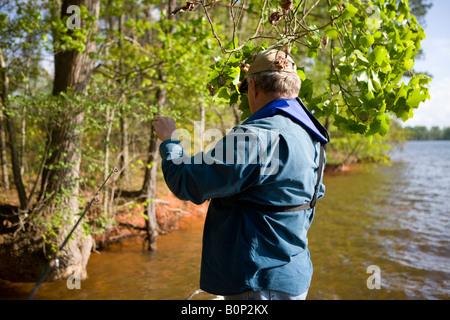 Ein erwachsener Mann hakt seinen Köder, der in einem Baum beim Angeln am Ufer des Sees Greenwood Stading auf einem Bass Boot gefangen wurde Stockfoto