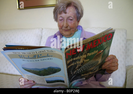 ältere Frau sitzt in ihrem Wohnzimmer lesen Zeitschrift Nature, New Mexico, USA Stockfoto