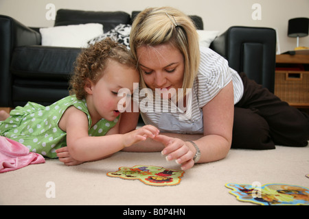 Mutter und Tochter spielen und lernen mit dem Einsatz von puzzles Stockfoto