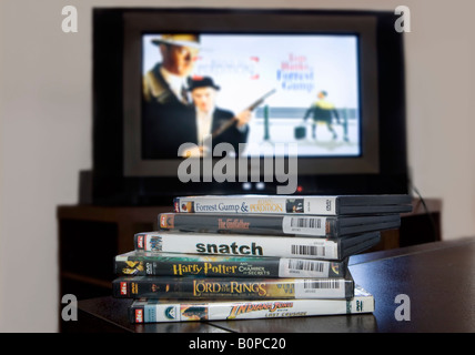 Ein Haufen von illegal raubkopierte DVDs der beliebtesten Filme mit einem Fernseher im Hintergrund Stockfoto