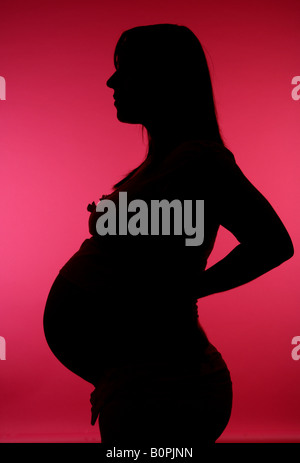 38 Woche schwangere Frau im Profil vor einem rosa Hintergrund abhebt Stockfoto