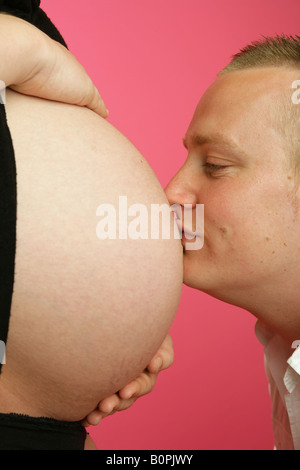 Ein Ehemann seine Frau schwanger ausgesetzt Bauch küssen. Stockfoto