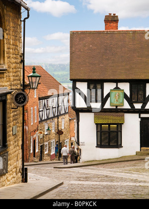 Touristen, die absteigend der historischen Straße von steilen Hügel in Lincoln, England, UK Stockfoto