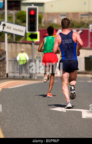 Männliche Läufer nachgestellte einen weibliche Läufer in Plymouth Marathon Stockfoto