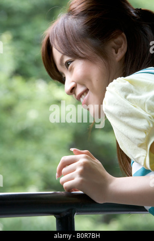 Junge Frau lehnt sich am Geländer Stockfoto
