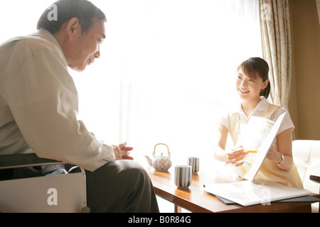 Krankenschwester mit Broschüre, älterer Mann im Rollstuhl Stockfoto
