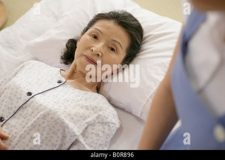 Porträt von senior Frau mit im Bett mit Krankenschwester auf ihrer Seite Stockfoto