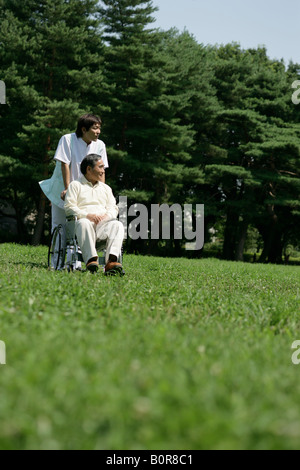 Krankenpfleger, die Unterstützung der ältere Mann im Rollstuhl in den park Stockfoto