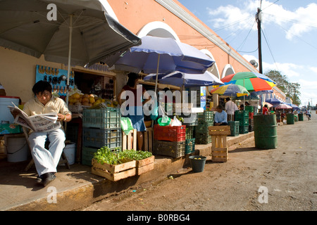 Blick auf die Citys Hauptmarkt Außenbereich mit einem Verkäufer lesen Zeitung bunte Sonnenschirme Obst und Gemüse und Kunden Stockfoto