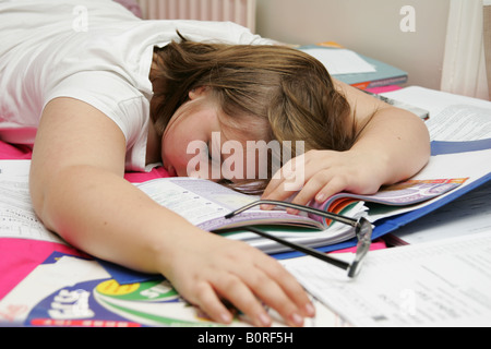 Teenager-Mädchen schlafend auf einem Haufen von Schulbüchern erschöpft von Überarbeitung Stockfoto