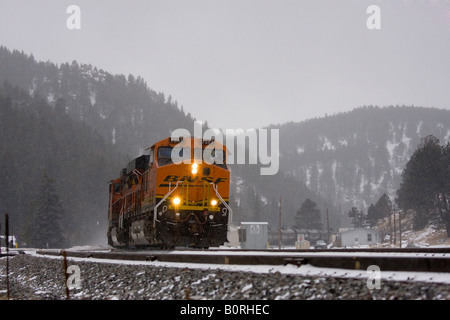 BNSF Güterzug dampft durch die Rocky Mountains während eines Schneesturms kalten Winter. Stockfoto