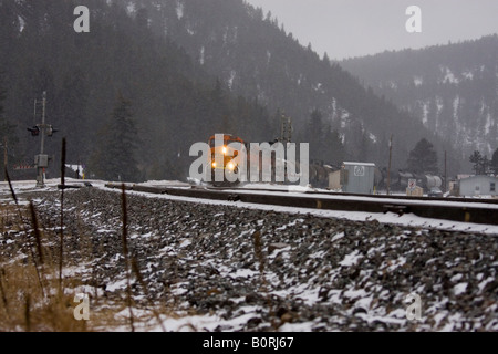 BNSF Güterzug dampft durch die Rocky Mountains während eines Schneesturms kalten Winter. Stockfoto