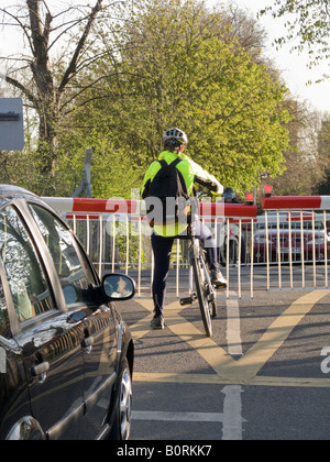 Radfahrer auf einem Bahnübergang warten, während die Barriere für das Bestehen eines Zuges ausfällt. Stockfoto