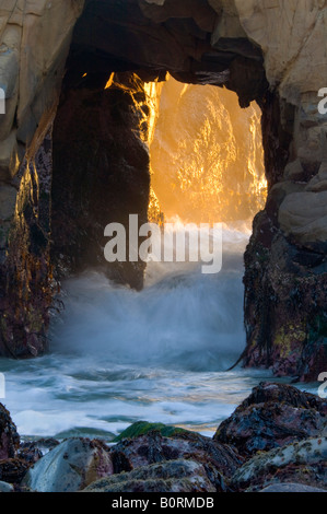 Abendlicht und Wellen kommen durch Loch in küstennahen Felsen Pfeiffer Beach Big Sur Kalifornien Stockfoto