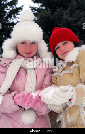 Porträt von zwei kleinen Mädchen in Winter Park holding Schneebälle Stockfoto