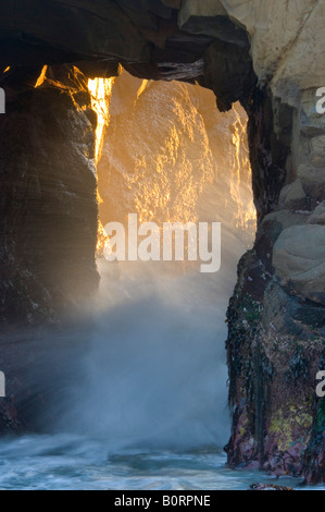 Abendlicht und Wellen kommen durch Loch in küstennahen Felsen Pfeiffer Beach Big Sur Kalifornien Stockfoto