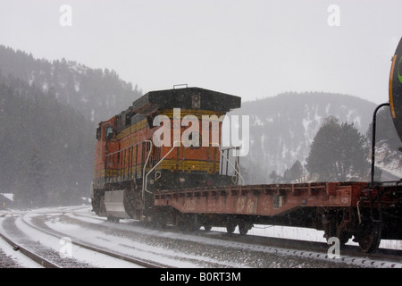 BNSF Güterzug dampft durch die Rocky Mountains während eines Schneesturms kalten Winter. Stockfoto