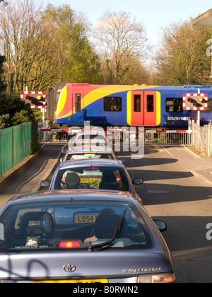 Autos warten auf eine Eisenbahn Bahnübergang Barriere während der Überfahrt Bahn durchläuft. Stockfoto