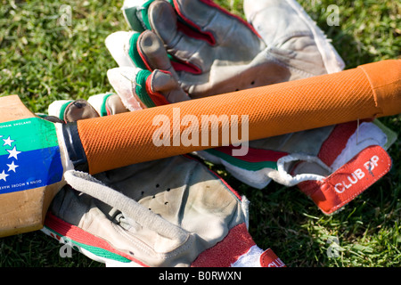 Kricketschläger und Handschuhe auf dem Rasen Stockfoto