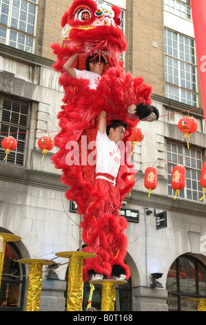 2 chinesische Drachen und Löwen tanzen Akrobaten auf Pole an die London Chinatown Chinese New Year Feierlichkeiten durchführen Stockfoto