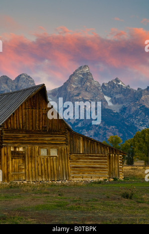 Rosa Wolken bei Morgendämmerung über alte hölzerne Scheune Berge und Bäume im Herbst entlang Mormone Zeile Grand Teton Nationalpark Wyoming Stockfoto