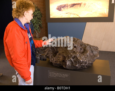 Kaukasische Frau (50–60) berührt den Meteoriten Holsinger am Meteor-Krater in Arizona USA Stockfoto