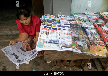 Eine Frau liest Zeitung in einer Zeitung stand in Yangon Myanmar, Mai Birma 2008 Stockfoto