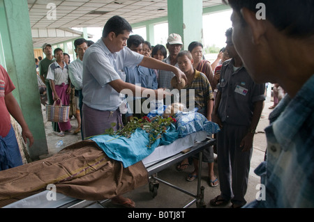 Ein Mann gießt coconut Flüssigkeit auf eine tote Person in ein buddhistisches Begräbnis, Yangon, Myanmar Birma Stockfoto