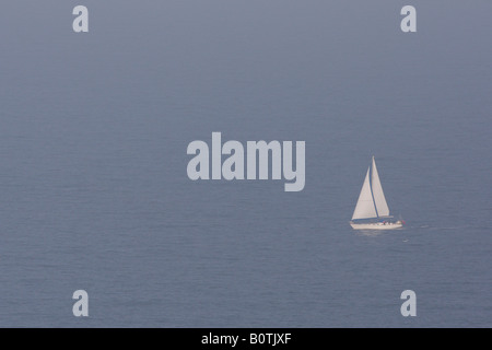 Kleinen Segelboot im nebligen blaue Meer vor Bempton Klippen yorkshire Stockfoto