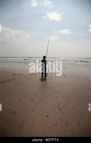 partielle Silhouette des Meeresangelns Mann unter der heißen Sonne und blauen Wolkenhimmel auf Zoll-Strang-Strand-Grafschaft Kerry-Dingle-Halbinsel Stockfoto