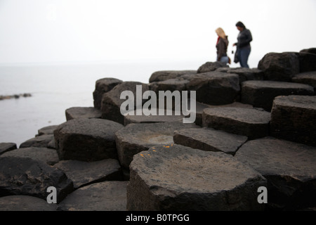 zwei weibliche Touristen Wandern rund um den roten Basalt sechseckigen Felsformationen an die Giants Causeway County Antrim-Nordirland Stockfoto