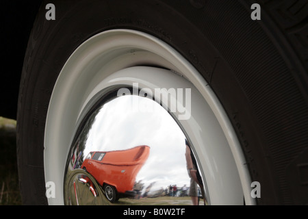 Eine VW Chrom Radnabe zeigt die Reflexion von einem anderen orange VW Transporter parkte in der Nähe von. Stockfoto
