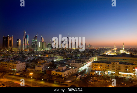 Erhöhten Blick auf die Wolkenkratzer an der Sheikh Zayed Road (L) und eine Moschee in Dubai, Vereinigte Arabische Emirate bei Einbruch der Dunkelheit beleuchtet. Stockfoto